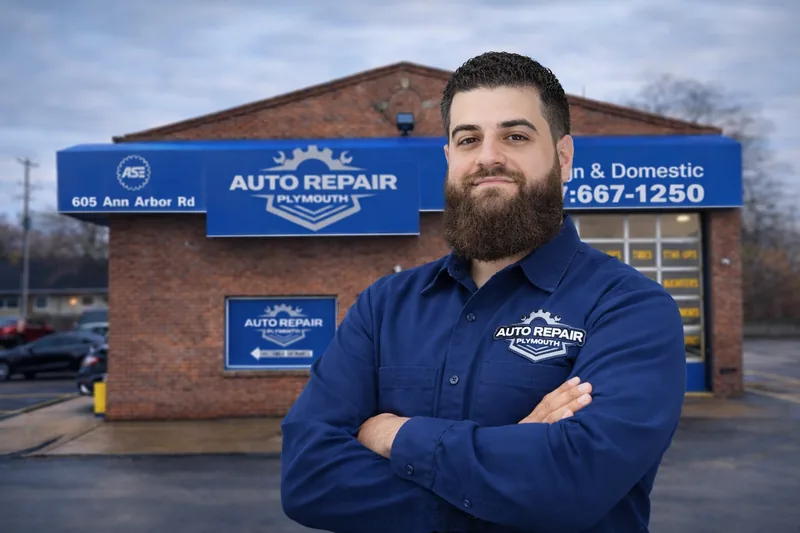 Abraham, owner of Plymouth Auto Repair & Muffler, standing outside the shop with blue awnings visible behind him